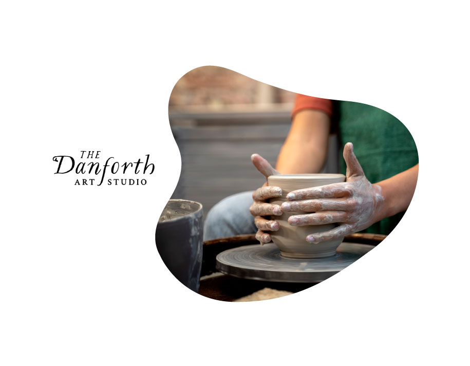 Hands working with clay at a pottery wheel